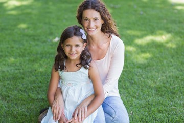 Happy mother and daughter sitting on the grass