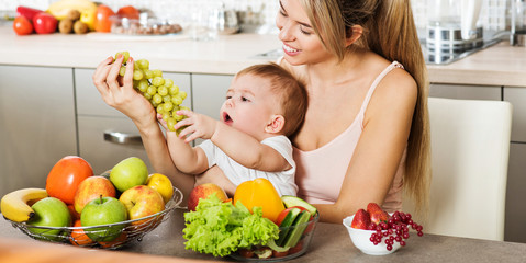 Happy young mother with a baby in the kitchen interior. Fresh ve