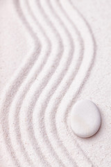 Zen garden with a wave lines in the sand with relaxing white sto