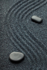 Fototapeta na wymiar Zen garden with a wave lines in the sand with relaxing black sto