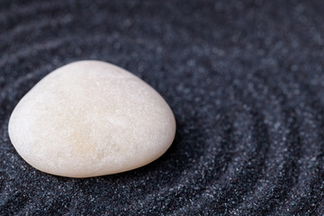 A beautiful silky marble stone in a zen garden with black sand