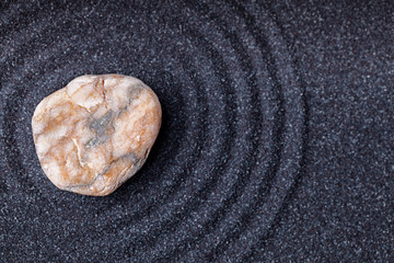 Fototapeta na wymiar A beautiful orange marble stone in a zen garden with black sand