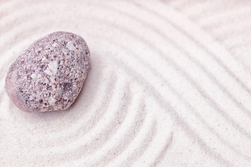 Fototapeta na wymiar A limestone stone in the fine sand of the zen garden with wavy