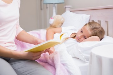 Obraz na płótnie Canvas Mother reading daughter a bedtime story