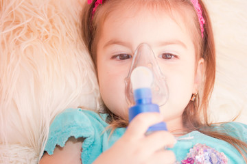 Little girl using an inhaler indoors