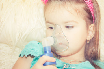 Little girl using an inhaler indoors