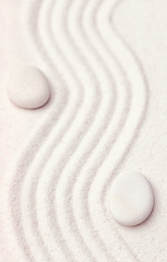 Zen garden with a wave lines in the sand with relaxing white sto