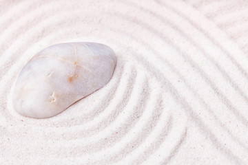 Fototapeta na wymiar A flat marble stone in the fine sand of the zen garden with wav