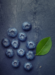A bunch of delicious blueberries with green leaf on a  black vin