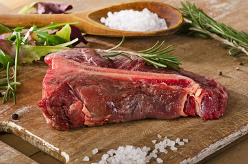 Raw beef t-bone steak on  old wooden table