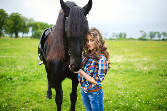 Young beautiful girl with frisian horse