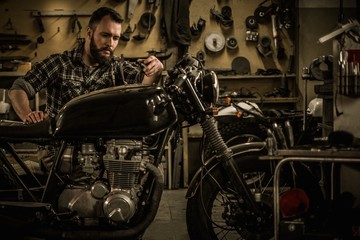 Naklejka premium Mechanik budujący motocykl cafe-racer w stylu vintage