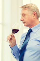 older man smelling red wine