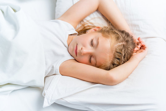little girl sleeping in white bed
