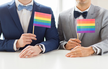 close up of male gay couple holding rainbow flags