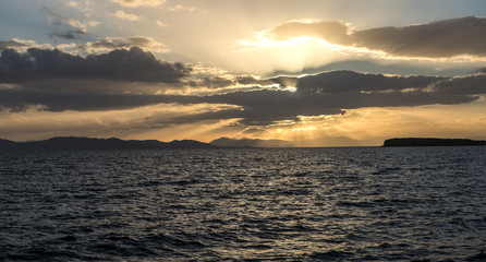 sunset behind the clouds over sea