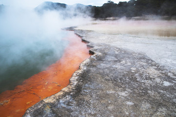 Colorful volcano lake with red sediments and steam