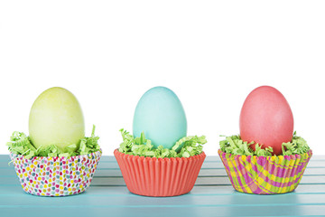 Dyed Easter eggs in a nest of green grass confetti and cup cake
