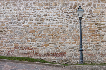 Old streetlamp with a stone wall in a background
