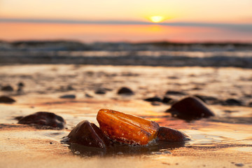Naklejka premium Bursztynowy kamień na plaży. Cenny klejnot, skarb. morze Bałtyckie