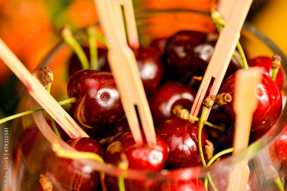 Wall mural A lot of cherries with toothpicks stuck in a glass bowl