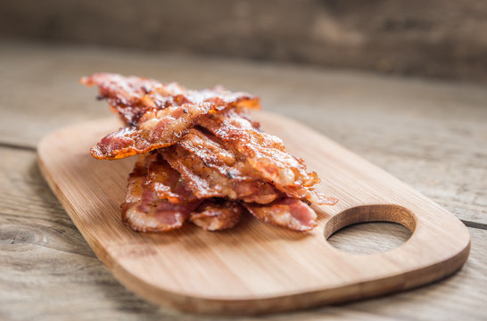 Stack of fried bacon strips on the wooden board