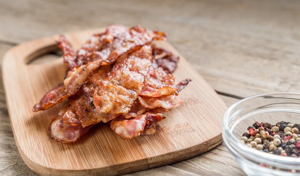 Stack of fried bacon strips on the wooden board