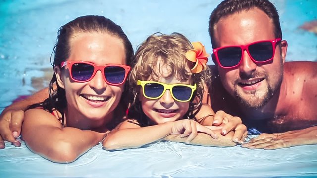 Happy family having fun in swimming pool. Slow motion