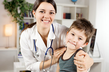 Happy female doctor with kid patient looking camera smiling