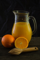 Jug with fresh orange juice, still life art on dark background