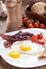 Fried egg and bacon on a plate with spices and vegetables