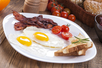 Fried egg and bacon on a plate with spices and vegetables