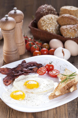 Fried egg and bacon on a plate with spices and vegetables