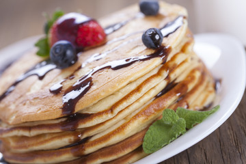 Delicious sweet American pancakes on a plate with fresh fruits