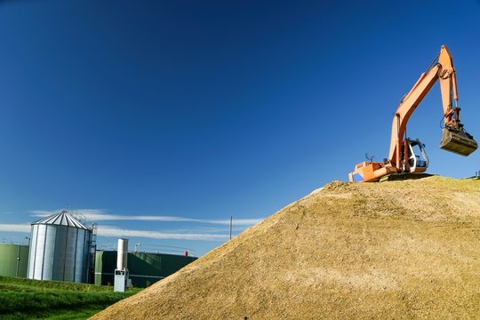 Silomaisernte , im Hintergrund eine Biogasanlage.