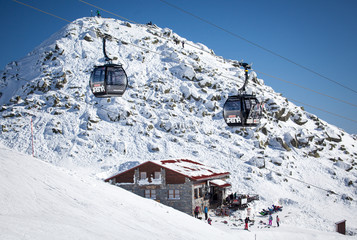 Cableway cabins moving above snowy slopes in the Low Tatras mountains near Chopok in Slovakia on a clear winter day at popular ski resort Jasna
