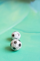Fototapeta na wymiar Toy soccer footballs on green canvas background.