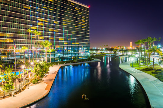 View of a modern building and Rainbow Lagoon Park at night, in L