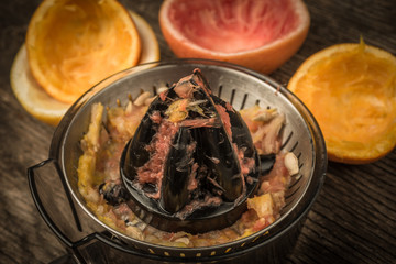 cut citrus fruit and juicer on wooden background