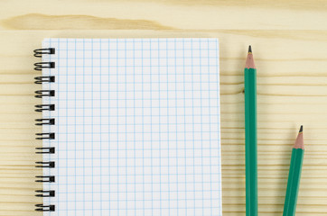 Blank notebook and pencils on wooden table