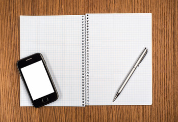 Smart phone, pen and notepad on wooden background close-up