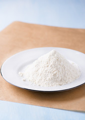 Fototapeta na wymiar Heap of wheat flour on white plate