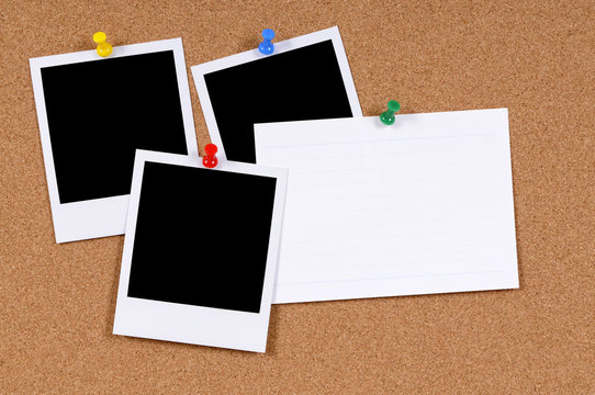 Several three polaroid style blank photo frame prints with office index card pinned to cork notice board background