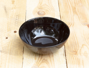 Empty black ceramic bowl on wood