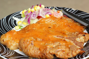 Steaks, french fries with vegetables salad on a plate.