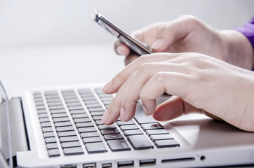 Closeup of businesswoman holding mobile phone on keyboard