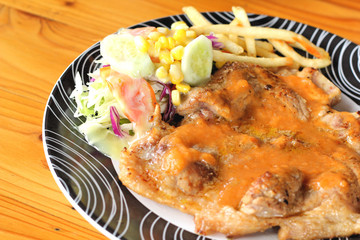 Steaks, french fries with vegetables salad on a plate.
