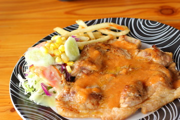 Steaks, french fries with vegetables salad on a plate.