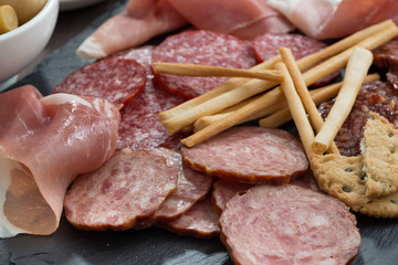 Assorted meat snacks, sausages on a blackboard, close-up