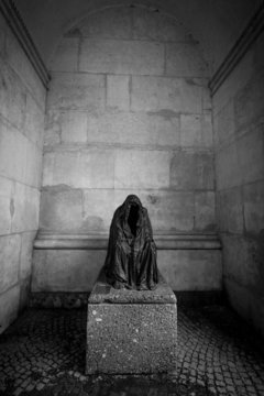 Monochrome photo of monument of scary ghost sitting on stone